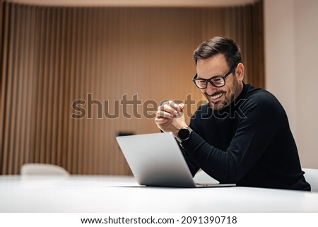Smilng adult man, joining the conference call in his office on the internet.