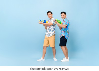 Smilng Happy Asian Male Friends Playing With Water Guns In Blue Isolated Background For Songkran Festival In Thailand And Southeast Asia