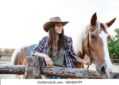 Smilng pretty young woman cowgirl standing with her horse on ranch - Powered by Shutterstock