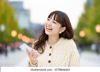 smily japanese woman uses smartphone
