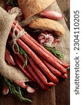 Smocked sausages with onion, garlic, pepper, and rosemary on an old wooden table. Top view.