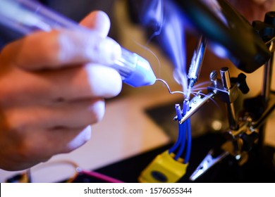 Smoke appears while soldering ESC and rotor wires with helper hands. Technology and electrical engineering concept. Autonomous vehicles like drones need a lot of soldering in building process