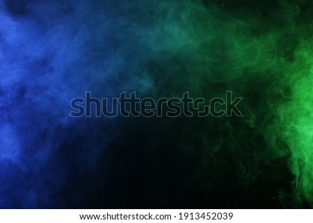 Smoke in blue green light on black background in darkness
