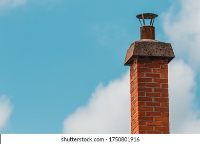 Smoke Brick Chimney On Rooftop Of Brick House With Blue Sky On Summer Day With Copy Space. Ideal For Background.