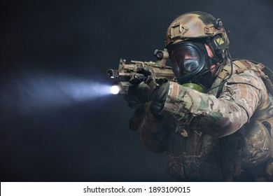 Smoke From Chemical Weapons And Tear Gas Impair The Visibility Of A Soldier In Full Military Gear, Helmet, Bulletproof Vest And Gas Mask, Holding A Machine Gun And Aiming At The Enemy