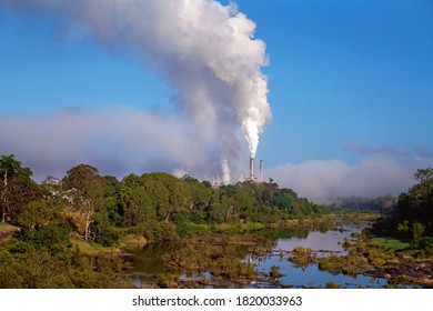 Smoke From The Chimney Of A Sugarcane Mill On A Creek Bank