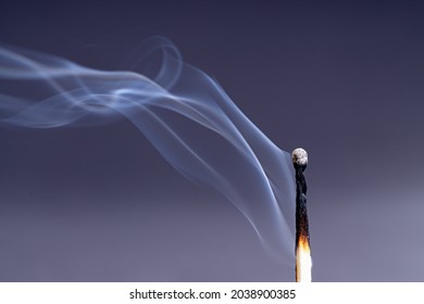 Smoke coming from an extinguished match against a dark purple background
