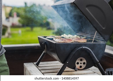 Smoke Coming Out Of A Smokestack Of A Small Black Smoker Grill Or Barbecue, Loaded With Chicken Meat And Vegetables.