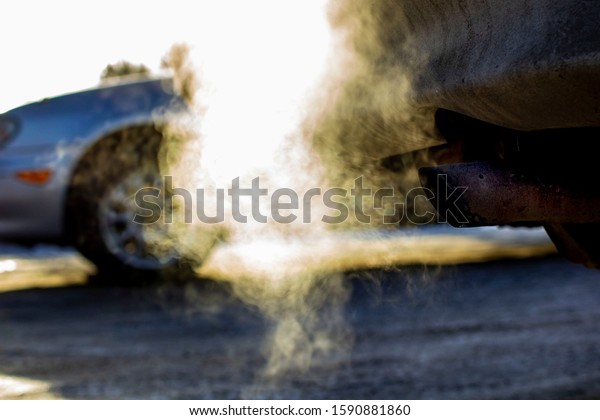 smoke from the exhaust pipe of the car in the\
winter cold season