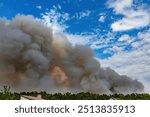 Smoke from a forest fire rises into the sky. Large plumes of smoke from a fire in a rural area