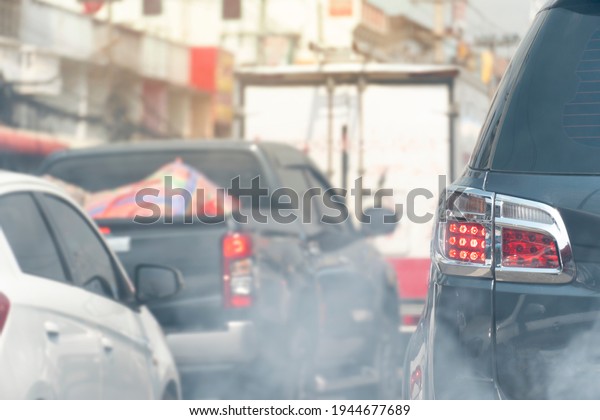 Aฺbstact smoke and pollution on the road. With\
Back side of the black car with open brake light. Traffic jams\
Along with the pollution environment with faint smoke in front of\
picture.