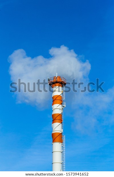 Smoke\
pollution. Smoke pipes against the blue\
sky.