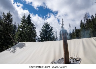 Smoke Rises From A Chimney On A Tent For Ventilation From The Camp Stove Inside The Tent, Staying Warm During Winter Camping