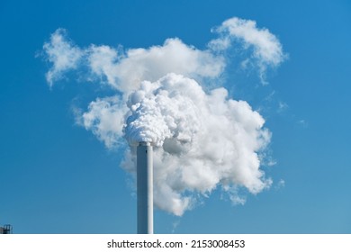 Smoke And Steam Rising From A Power Plant Into The Air, Blue Sky Background, Concept For Environmental Pollution 