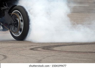 Smoke from under the rear wheel of a motorcycle with the drift.  Moto drift