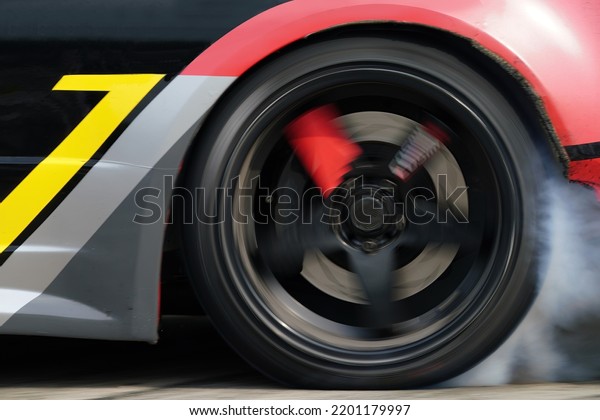 Smoke from under\
the wheels slip spin turning on road surface burning tire of drift\
sport car motor sport.  