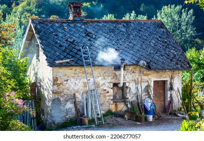 The Smoke Of The Wood Stove Comes Out Of The Chimney Of An Ancient House In The Mountains