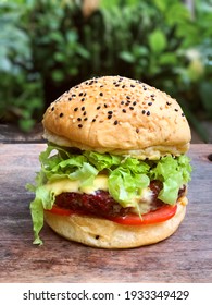 Smoked Artisan Burger With Salad And American Cheese On Wooden Board