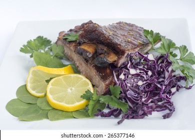 Smoked Barbecue Baby Back Ribs Decorated With Spinach Red Cabbage Lemon And Parsley In A White Ceramic Plate