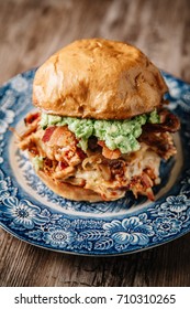 Smoked Bbq Chicken Sandwich With Sautéed Onions, Bacon, Pepper Jack Cheese And Guacamole Spread On Rustic Background