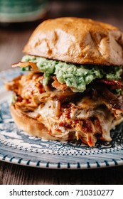 Smoked Bbq Chicken Sandwich With Sautéed Onions, Bacon, Pepper Jack Cheese And Guacamole Spread On Rustic Background