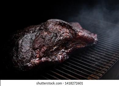 Smoked Beef Brisket On A Dark Smoker Barbecue, In A Slow Cooking Background