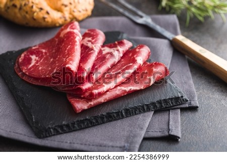 Smoked bresaola. Italian appetizer. Dried beef meat on the cutting board.