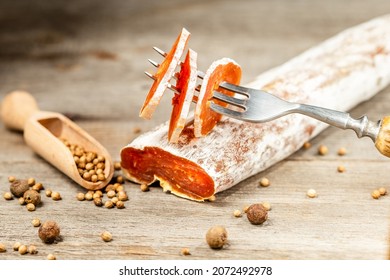 Smoked Chicken Meat Sausage Covered With Edible Penicillin Mold Sliced On The Fork And Pepper Seeds On The Wooden Table