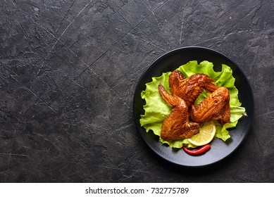 Smoked Chicken Wings With Ketchup And Chili Hot Peppers. Black Concrete Background. Barbecue. Top View.