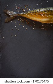 Smoked fish with spices on a black background.