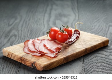 Smoked Ham Prsut With Cherry Tomatoes And Chili, On Wooden Table