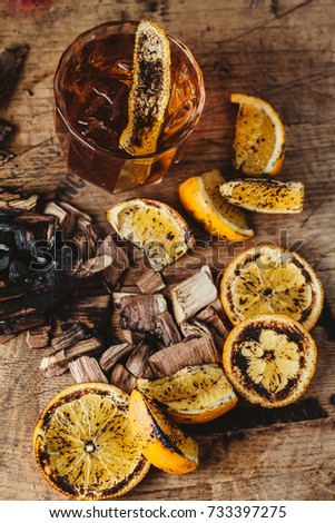 Smoked old fashioned cocktail garnished with an orange peel on dark wooden background