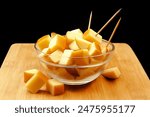 SMOKED PROVOLONE CHEESE CHOPPED IN BOWL ON WOODEN BOARD AND DARK BACKGROUND