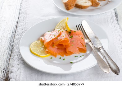 smoked salmon with lemon slices on white plate