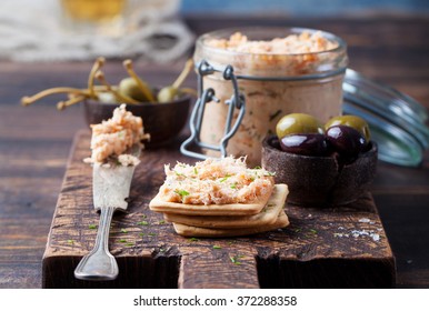 Smoked Salmon And Soft Cheese Spread, Mousse, Pate In A Jar With Crackers, Olives And Capers On A Wooden Background