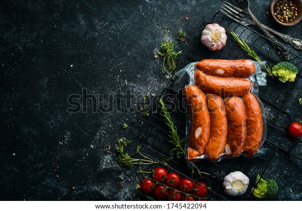 Smoked sausages in vacuum packaging. Top\
view. On a black\
background.