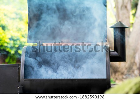 A smoker starting the smoking process, smoke coming from grill.