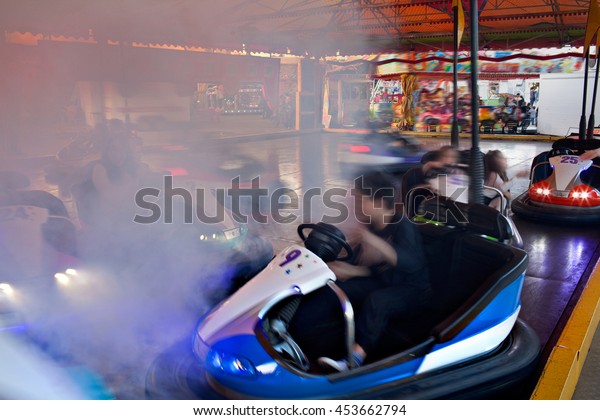 Smokey fun park bumper cars ride under\
colorful marquee, outdoors activities. Active bumper cars motion\
blur entertainment in fun amusement park, funfair rides moving fast\
bright lights,\
lifestyle.