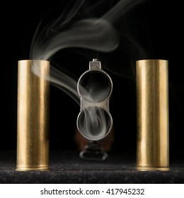 Smoking barrel of rifle and two shells on black background