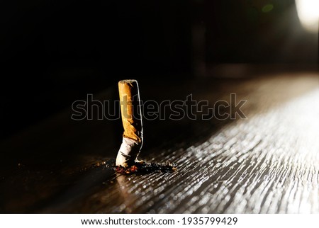 A smoking burning cigarette on a dark floor background. Stop smoking concept