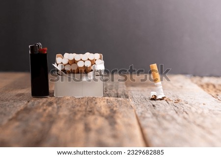 Smoking cessation concept.  Open pack of cigarettes and lighter on a wooden table with one cigarette smushed or crumbled.