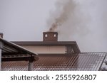 a smoking chimney in a single-family house in the countryside. gestures, black poisonous smoke from the chimney