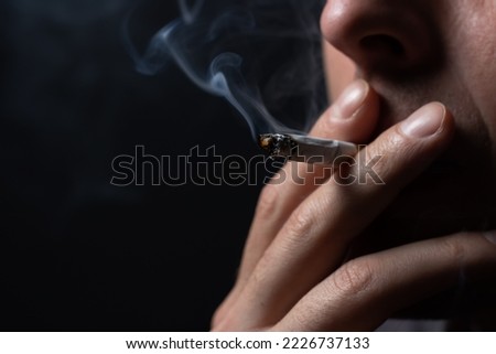 Smoking cigarette in the hand of young man close up.