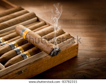 smoking cuban cigar over box  on wood background