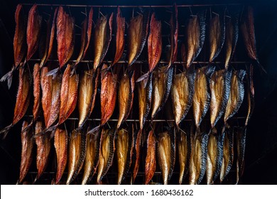 Smoking fish filets hanging side by side in a smoker. Cold smoked mackerel pieces for sale in fish market