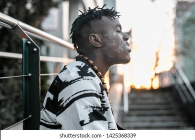 Smoking guy. Young african man smoking on the city sunny street