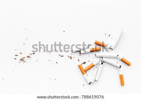 Smoking. Half-smoked cigarettes with ash on white background top view copyspace