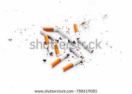 Smoking. Half-smoked cigarettes with ash on white background top view