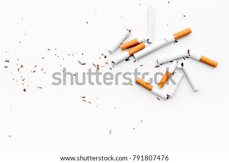 Smoking. Half-smoked cigarettes with ash on white background top view copy space