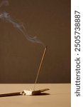 
smoking incense stick on a beige background. Aromatherapy, Smoking while burning incense. smoke for prayers and meditation. prayer to buddha. incense for relaxation and yoga